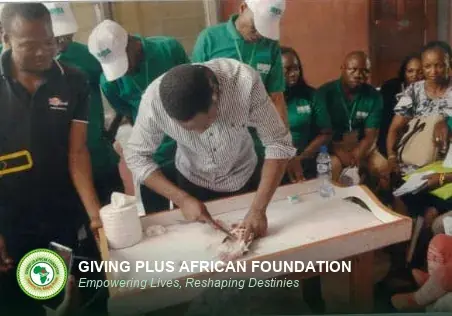 A facilitator demonstrating fish handling at a table as trainees watch